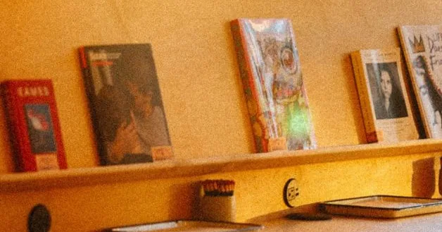 Empty café counter with chairs and magazines on a shelf in warm evening light